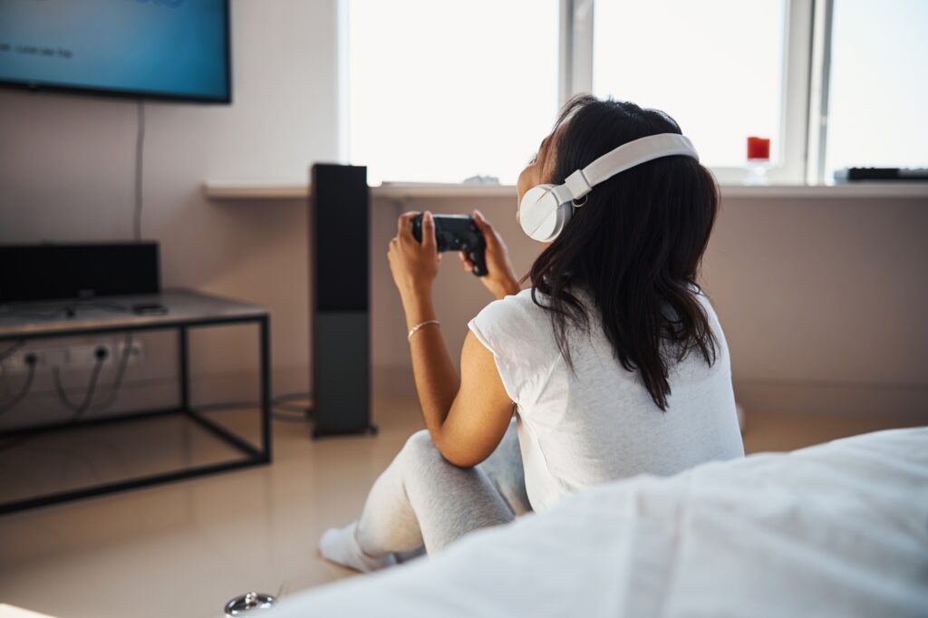 Young woman in headphones playing video game at home